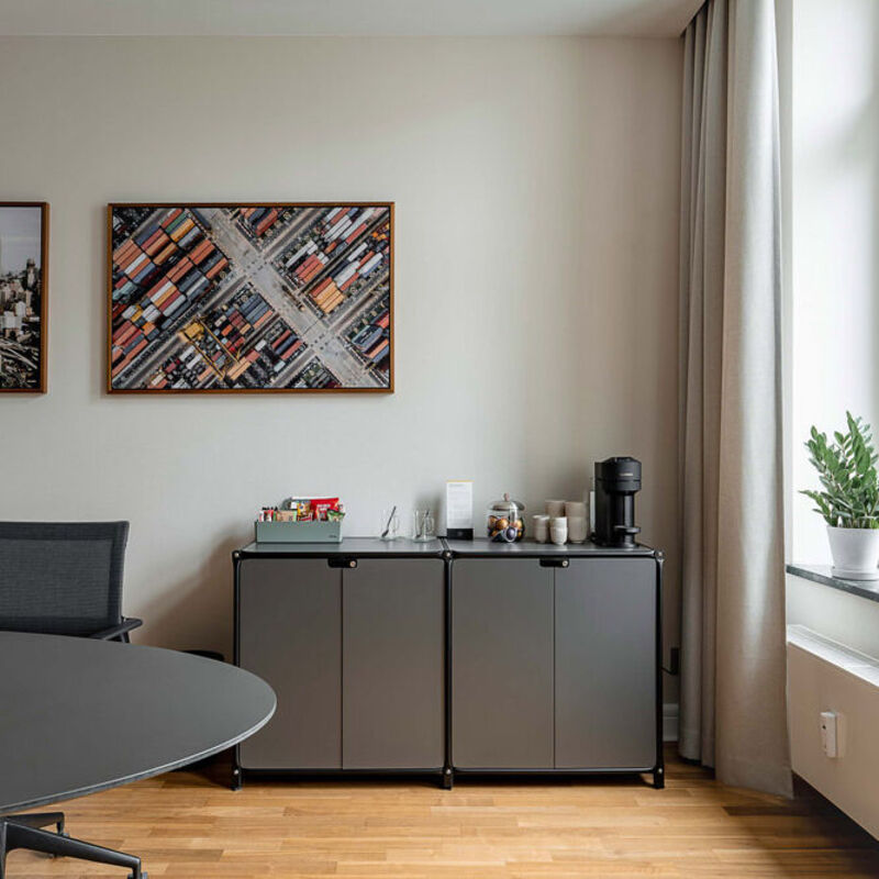 Besprechungsraum mit ovalem Tisch, Sideboard mit Kaffeemaschine und Wandbildern im Office Club Berlin Mitte
