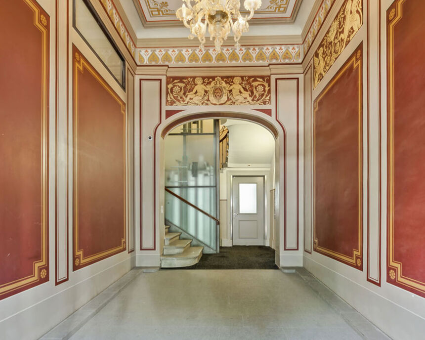 Prunkvolle historische Eingangshalle mit roten Wänden und Kronleuchter im Office Club Zürich