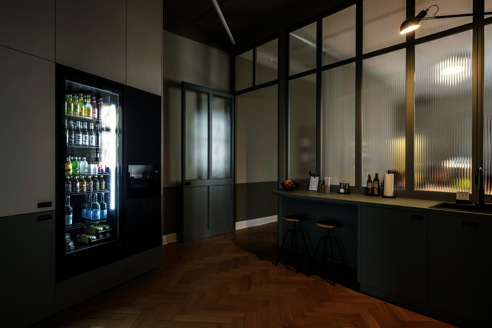 Küche mit beleuchtetem Getränkekühlschrank und Einbauschränken im Office Club Berlin Kurfürstendamm