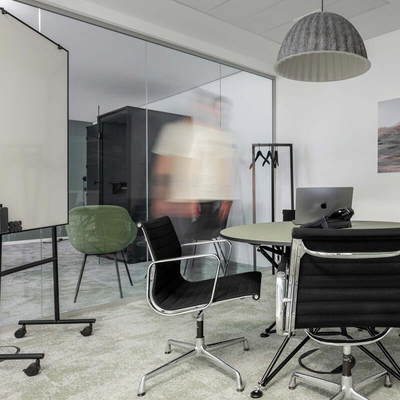 Tagesbüro mit Glaswand, Hängeleuchte und Bürostühlen im Office Club