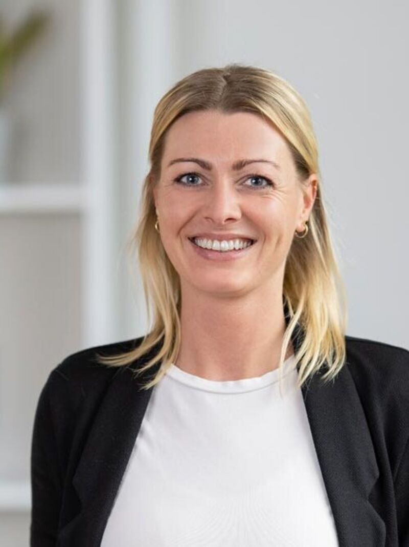 Lächelnde Office Club Mitarbeiterin im schwarzen Blazer