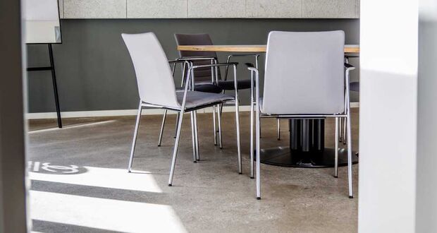 Weiße Stühle an einem Tisch auf Betonboden