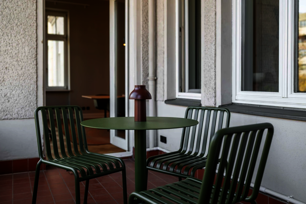 Balkon mit grünen Metallstühlen und Bistrotisch im Office Club Berlin Kurfürstendamm