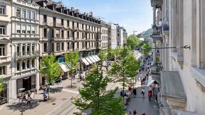 Einkaufsstraße in Zürich mit historischen Geschäftshäusern und Bäumen
