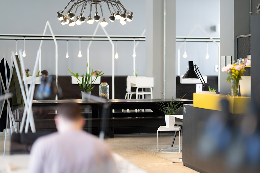 Coworking-Bereich mit langen Tischen und Hängeleuchten im Office Club Berlin Prenzlauer Berg