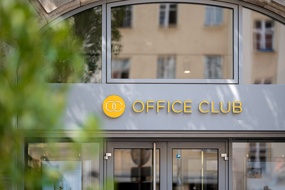 Eingang des Office Club Berlin Prenzlauer Berg mit goldenem Logo-Schriftzug über der Glastür