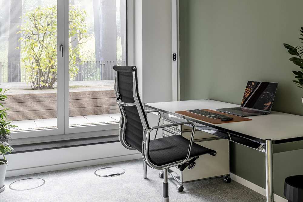 Büro mit Schreibtisch, schwarzem Bürostuhl und bodentiefem Fenster im Office Club Düsseldorf