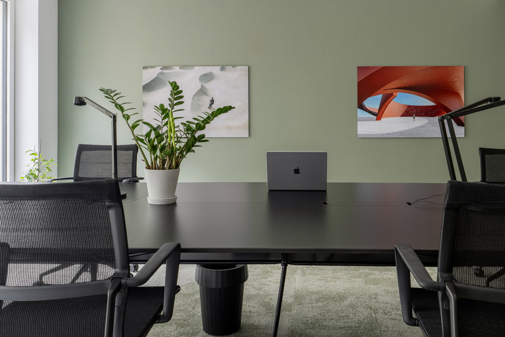 Open-Space-Arbeitsplatz mit Laptop, Pflanze und Wandbild im Office Club Düsseldorf