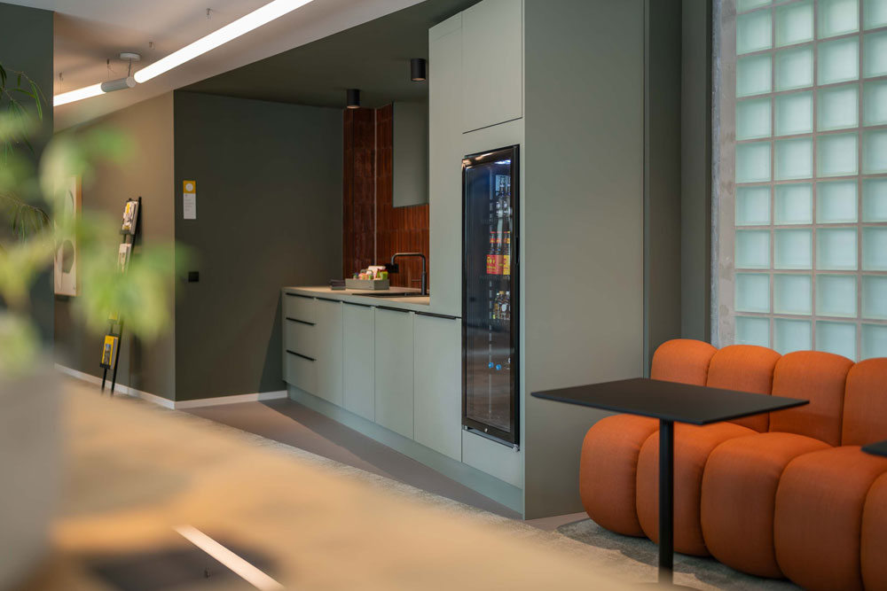Küche mit orangefarbener Sitzbank, Stehtisch und Glasbausteinwand im Office Club Frankfurt