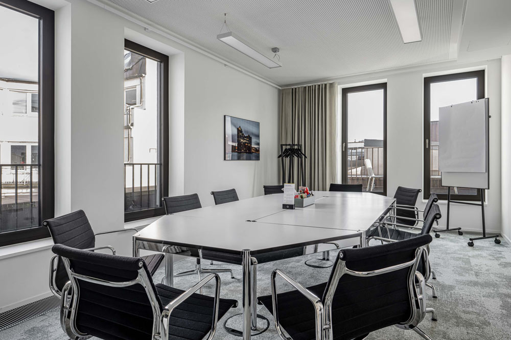 Besprechungsraum mit langem Tisch, schwarzen Stühlen und Whiteboard im Office Club Hamburg