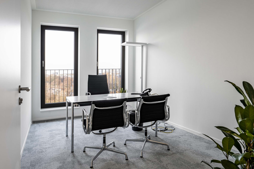 Büro mit zwei Schreibtischen, schwarzen Bürostühlen und Fenstern im Office Club Hamburg