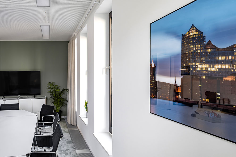 Konferenzraum mit Bildschirm und Wandbild der Elbphilharmonie im Office Club Hamburg