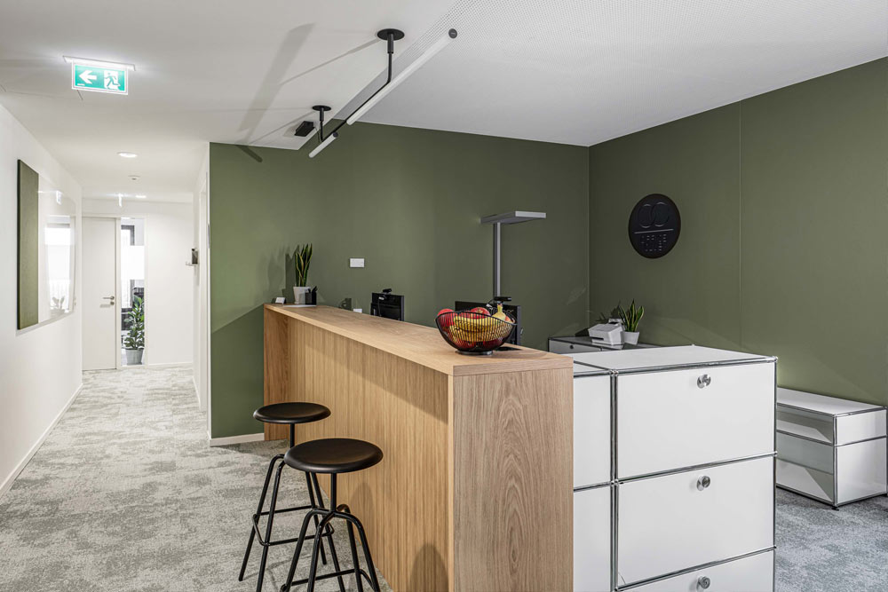 Empfang mit Holztheke und Barhockern vor grüner Wand im Office Club Hamburg