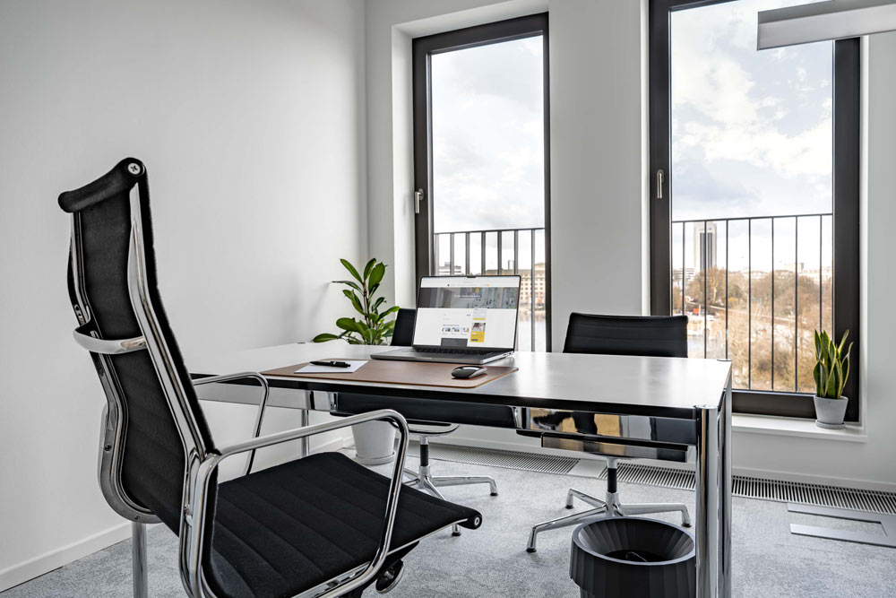 Büro auf Zeit mit Schreibtisch, schwarzem Chefsessel und Balkonfenster im Office Club Hamburg