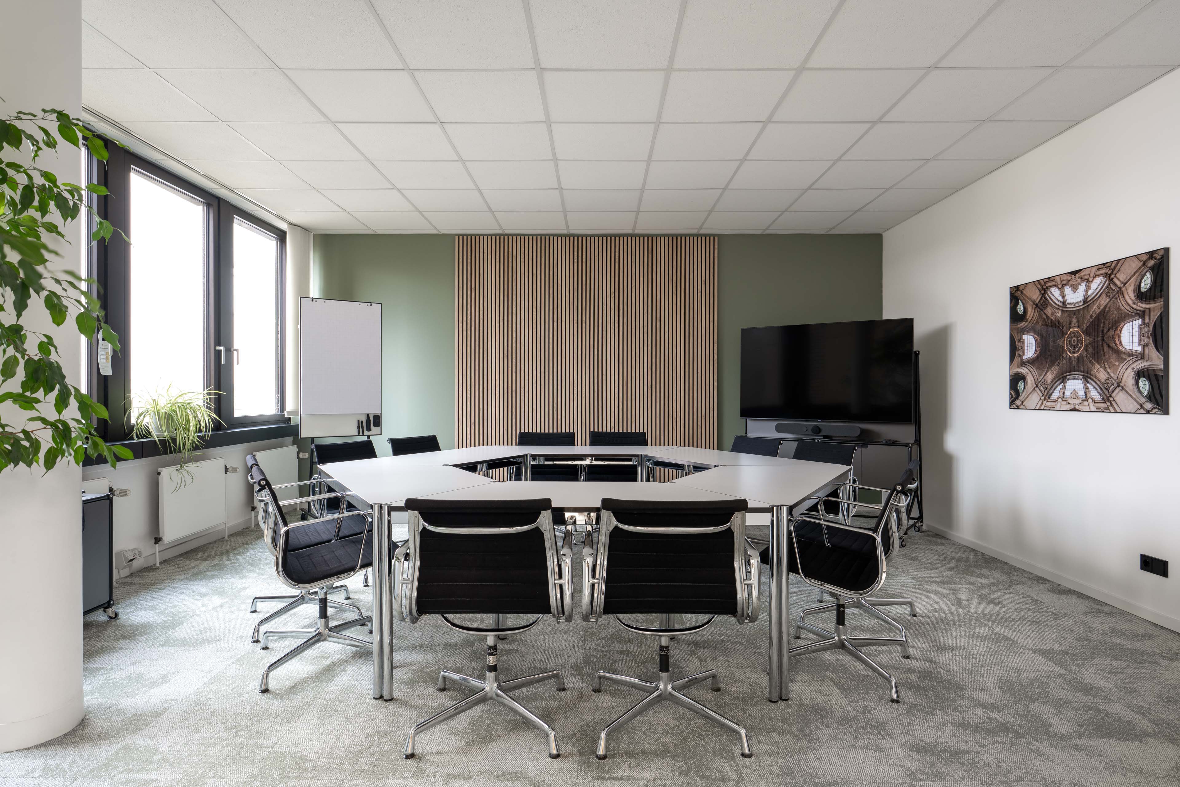 Großer Konferenzraum mit Tischanordnung, schwarzen Stühlen und Holzlamellenwand im Office Club Hannover