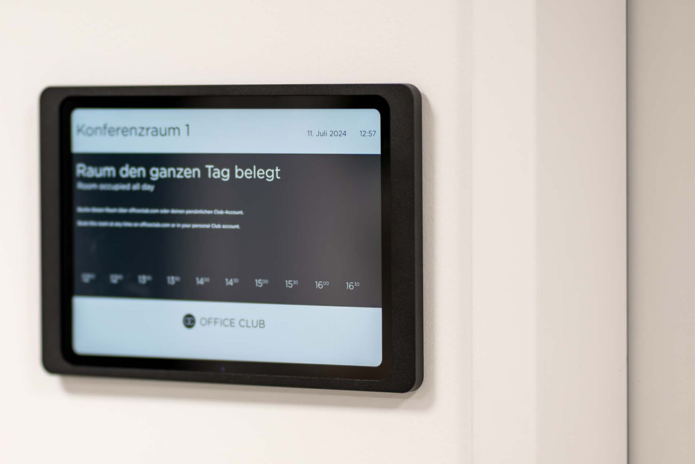 Raumbuchungs-Tablet mit der Anzeige „Konferenzraum 1 – Raum den ganzen Tag belegt“ im Office Club Hannover