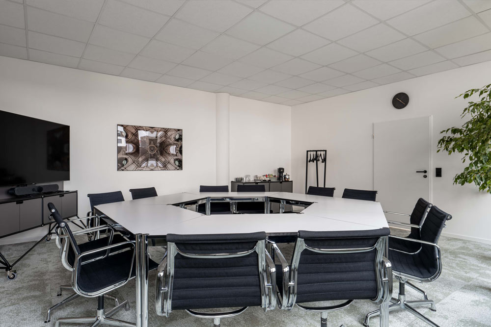 Seminarraum mit Tischgruppe, schwarzen Stühlen und Bildschirm im Office Club Hannover