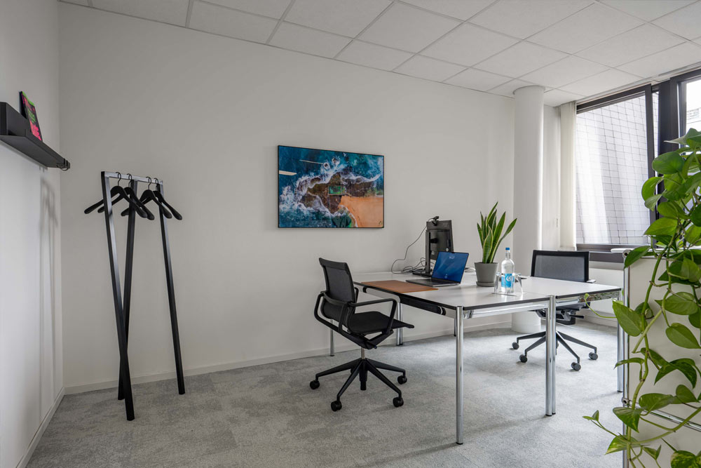 Tagesbüro mit Schreibtisch, Bürostuhl, Garderobe und Wandbild im Office Club Hannover