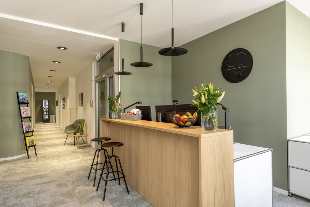 Empfangstheke aus Holz mit Blumen und Barhockern im Office Club Köln Friesenplatz