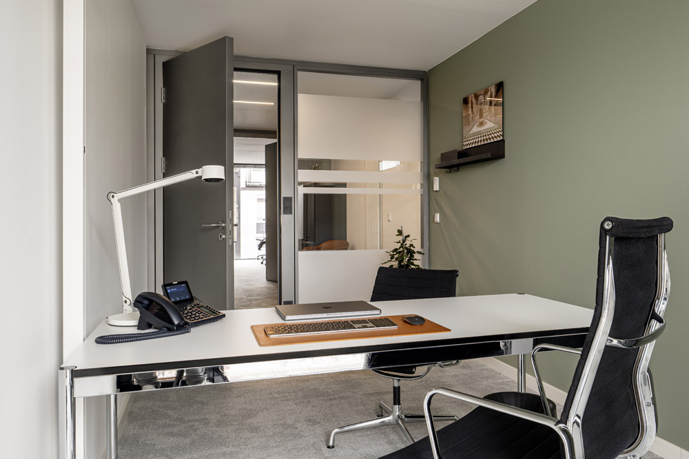 Büro mit Schreibtisch, schwarzem Chefsessel, Lampe und Telefon im Office Club München