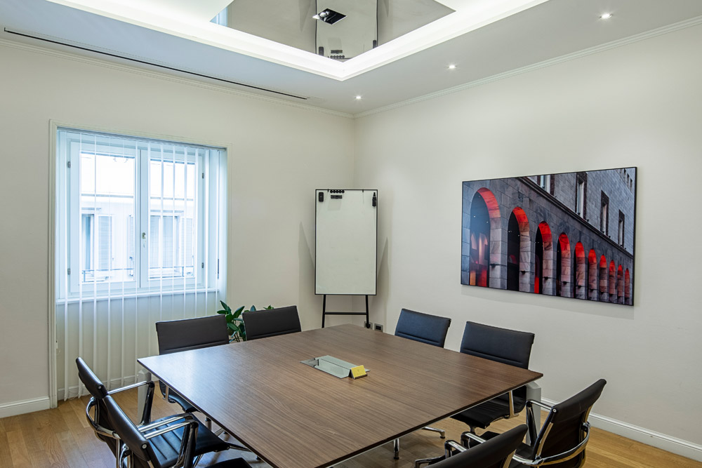 Besprechungsraum mit Holztisch, Flipchart und rotem Wandbild im Office Club Mailand Via Bagutta