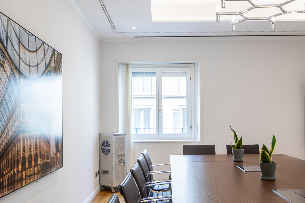 Konferenzraum mit Holztisch, schwarzen Stühlen und großem Wandbild im Office Club Mailand Via Bagutta
