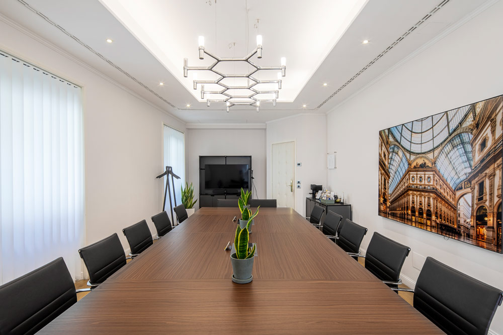 Seminarraum mit langem Holztisch, schwarzen Stühlen und Wandbild der Galleria Vittorio Emanuele im Office Club Mailand Monte Napoleone
