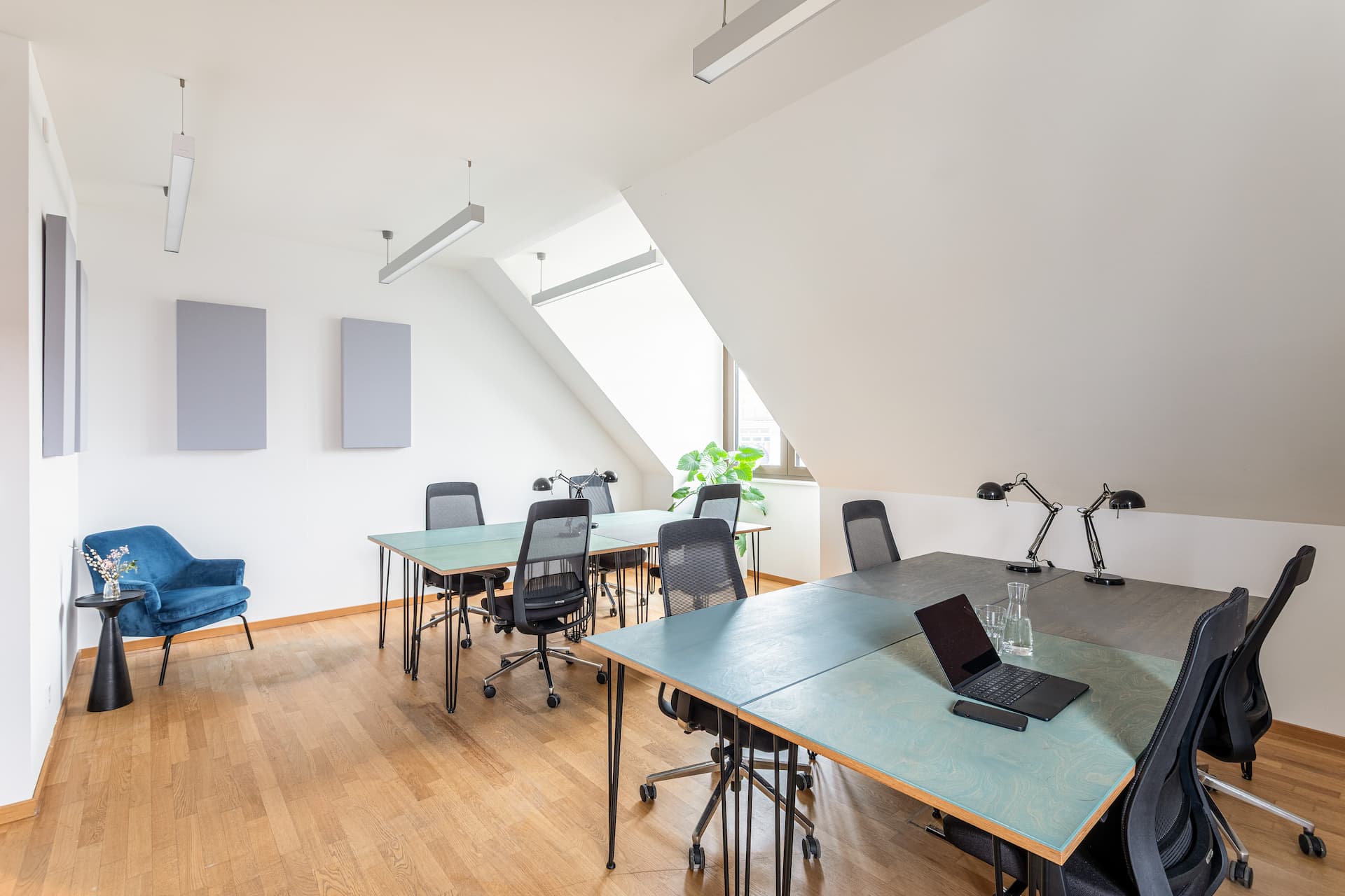 Teambüro unter Dachschrägen mit Schreibtischen und blauem Sessel im Office Club Potsdam