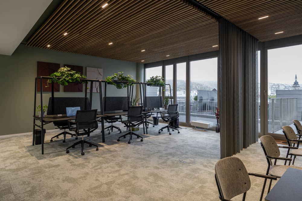 Coworking-Bereich mit Arbeitsplätzen unter einer Holzlamellendecke im Office Club Stuttgart