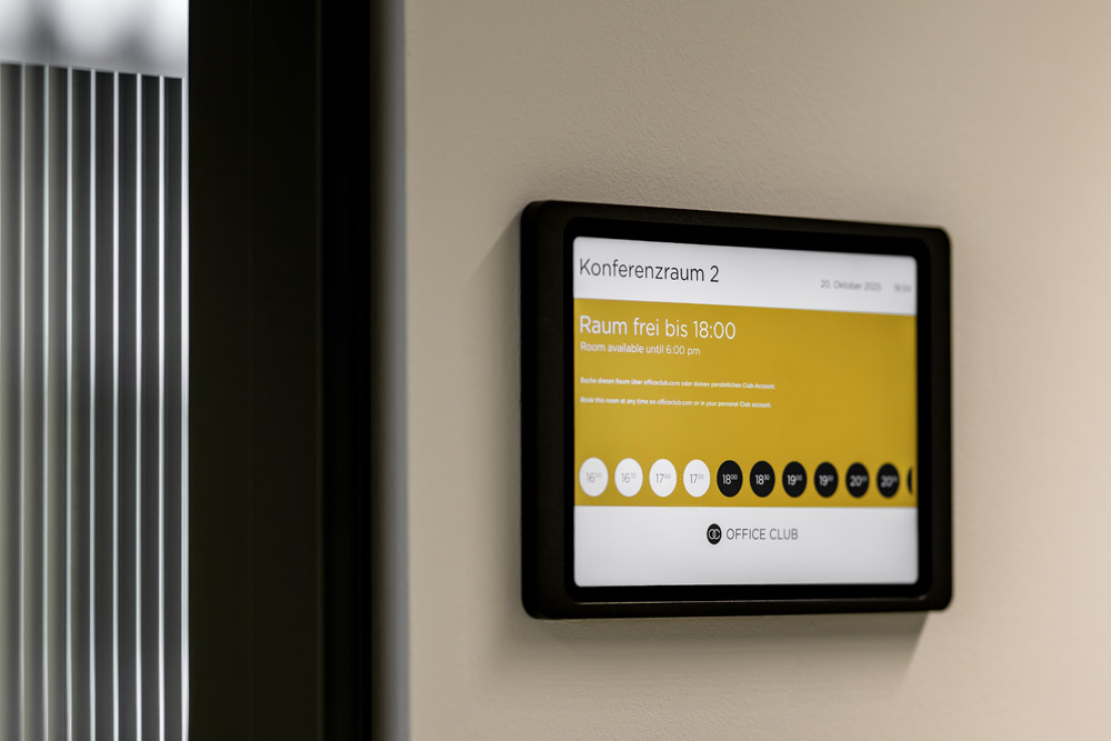 Raumbuchungsdisplay neben der Tür eines Konferenzraums im Office Club Stuttgart