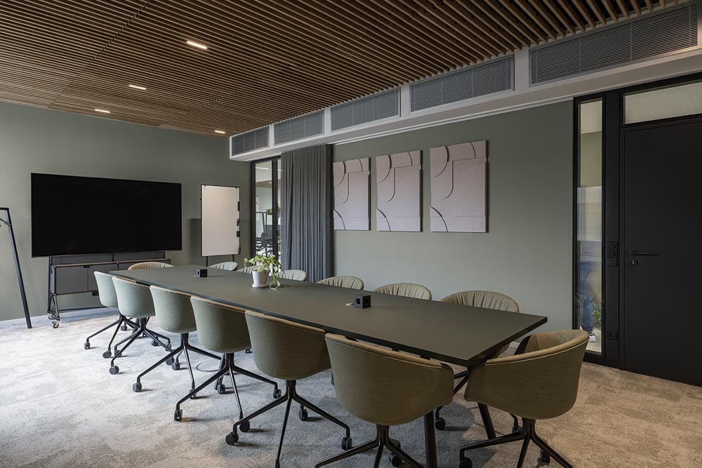 Großer Konferenzraum mit langem Tisch, beigen Stühlen und Holzlamellendecke im Office Club Stuttgart
