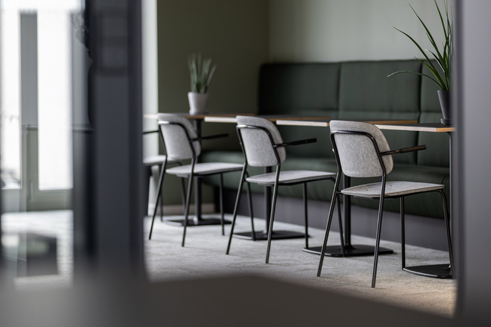 Veranstaltungsfläche mit Stehtischen, Stühlen und grüner Sitzbank im Office Club Stuttgart
