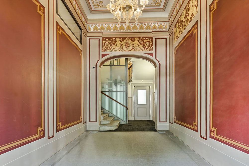 Prunkvolle historische Eingangshalle mit roten Wänden und Kronleuchter im Office Club Zürich