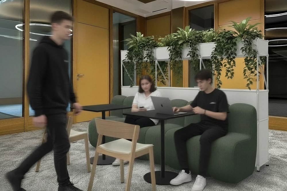 Menschen arbeiten in der Lounge mit grünem Sofa und Pflanzen im Office Club Zürich
