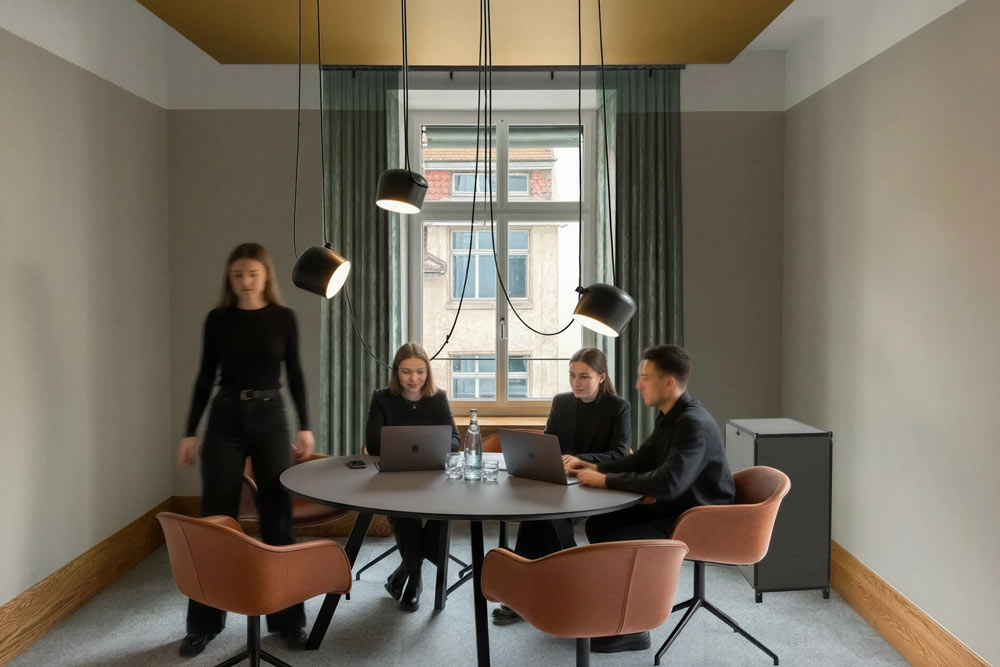Besprechung am runden Tisch mit cognacfarbenen Stühlen und Hängeleuchten im Office Club Zürich