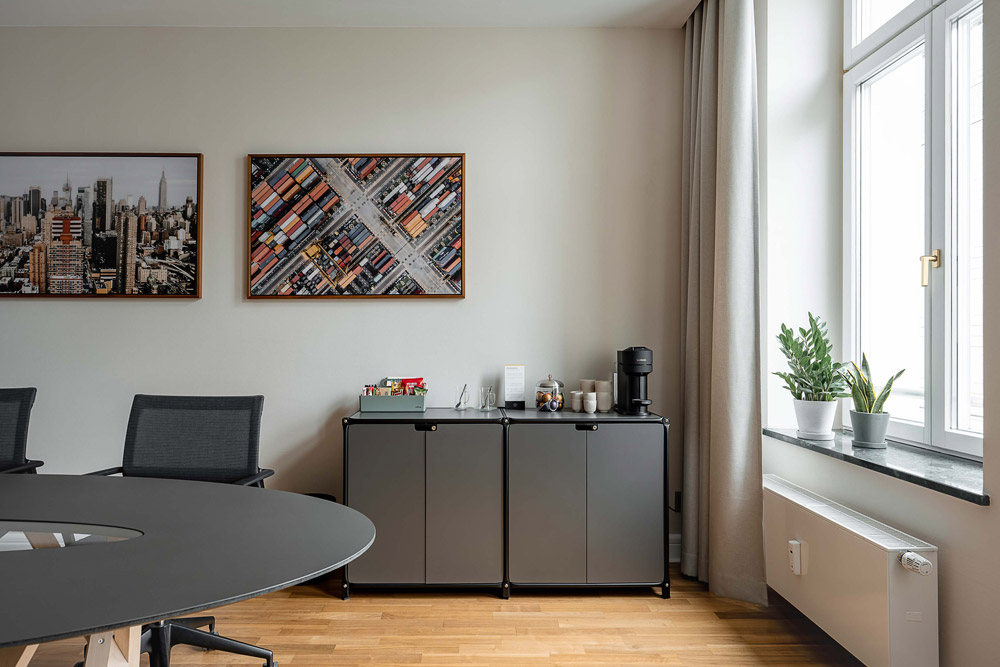 Besprechungsraum mit ovalem Tisch, Sideboard mit Kaffeemaschine und Wandbildern im Office Club Berlin Mitte