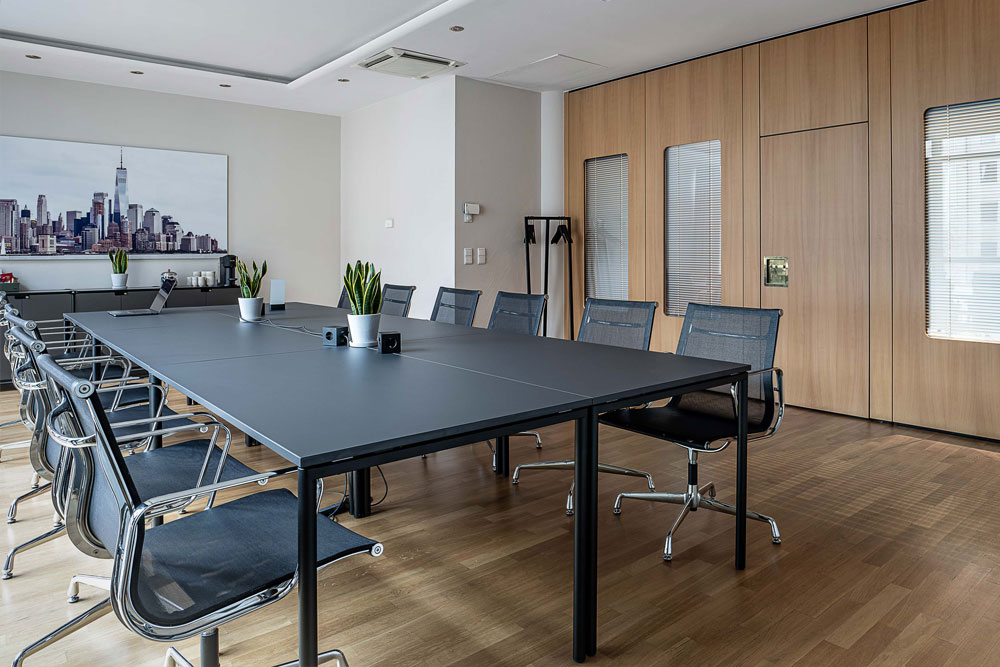 Seminarraum mit Tischreihen, schwarzen Bürostühlen und Skyline-Wandbild im Office Club Berlin